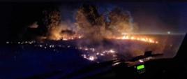 Zdjęcie palącego się zboża wykonane z wozu strażackiego w porze nocnej