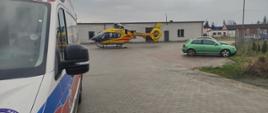Parking przy budynku, w którym doszło do zasłabnięcia mężczyzny, śmigłowiec wylądował na środku parkingu, a obok znajduję się przybyły na miejsce ambulans.