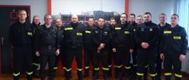 Strażacy w mundurach stoją w szeregu.
