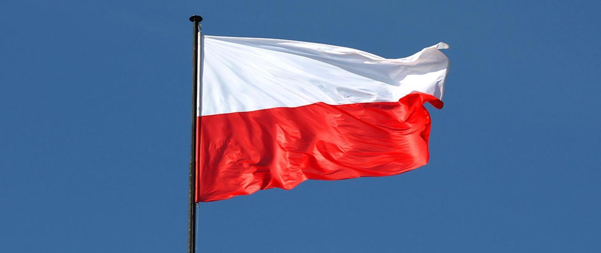Flaga Polski powiewająca na niebieskim tle nieba