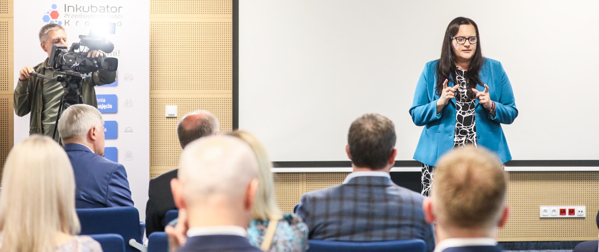 W sali konferencyjnej wiceminister Małgorzata Jarosińska-Jedynak mówi do osób siedzących przed nią na krzesłach