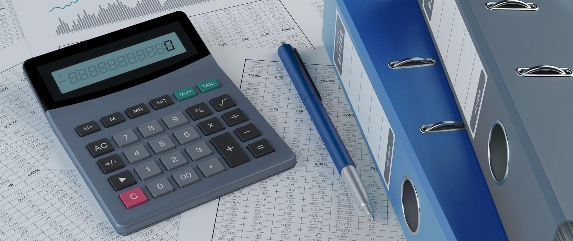 Wydruki tabel i wykresów, obok których znajdują się kalkulator, długopis oraz dwa niebieskie segregatory.