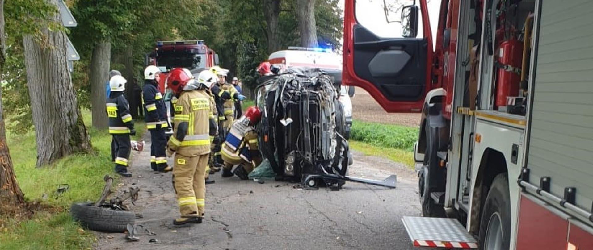 Zdjęcie przedstawia strażaków przy wraku pojazdu