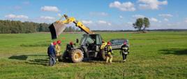 Strażacy podczas akcji gaszenia ładowarki kołowej palącej się na polu