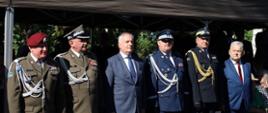 Pomorski komendant wojewódzki Państwowej Straży Pożarnej stoi wspólnie z zaproszonymi gośćmi w rzędzie.