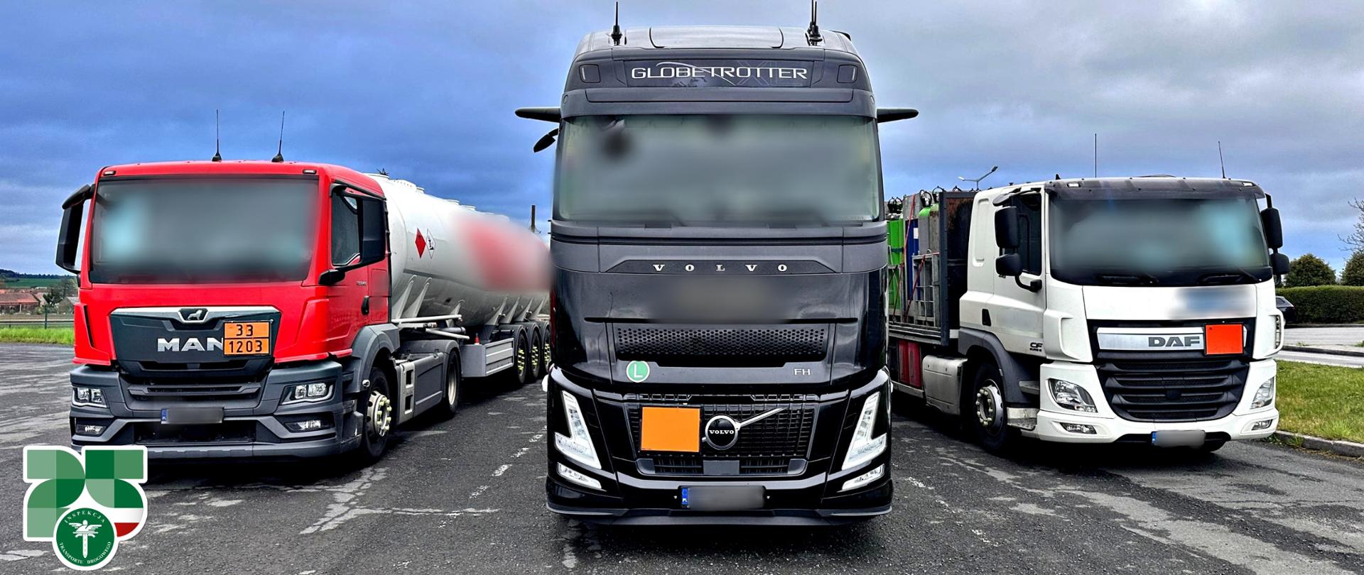 Trzy ciężarówki zaparkowane obok siebie na parkingu pod pochmurnym niebem. Pośrodku czarny ciągnik siodłowy Volvo, po lewej czerwony MAN z cysterną, po prawej biały DAF. Na dole logo Inspekcji Transportu Drogowego.