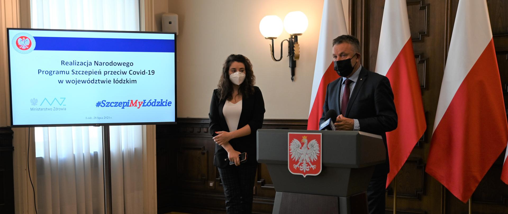 Wicewojewoda łódzki Karol Młynarczyk wraz z pełnomocnik wojewody łódzkiego ds. szczepień przeciw Covid-19 Jolanty Kowalik-Gęsiak stoją i zabierają głoś na temat realizacja Narodowego Programu Szczepień