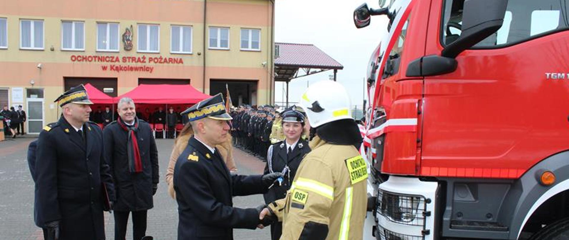 Komendant główny PSP podaje rękę kierowcy samochodu który został przekazany dla jednostki