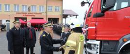 Komendant główny PSP podaje rękę kierowcy samochodu który został przekazany dla jednostki