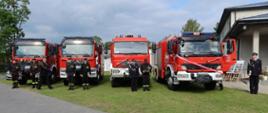 cztery samochody strażackie stojące obok siebie, przed nimi kilku strażaków