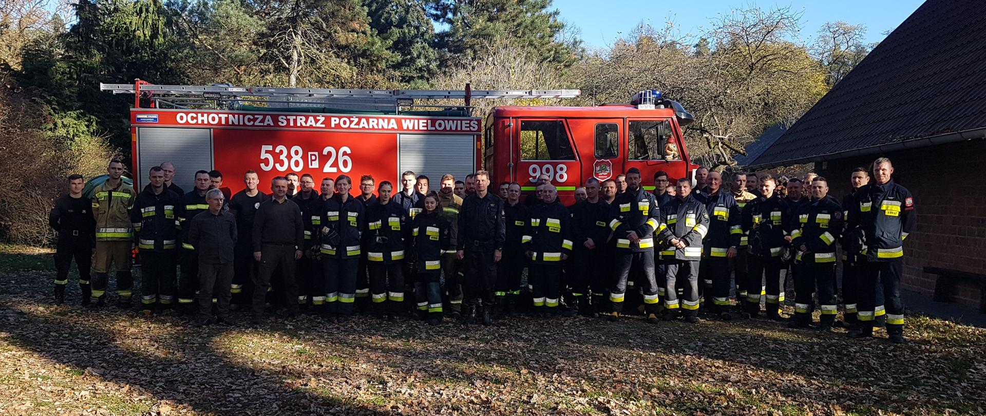 Uczestnicy ćwiczeń na tle samochodu pożarniczego.