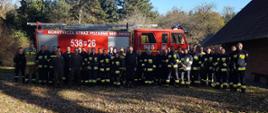 Uczestnicy ćwiczeń na tle samochodu pożarniczego.
