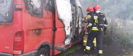 Dwóch strażaków w sprzęcie ochrony dróg oddechowych podczas gaszenia busa