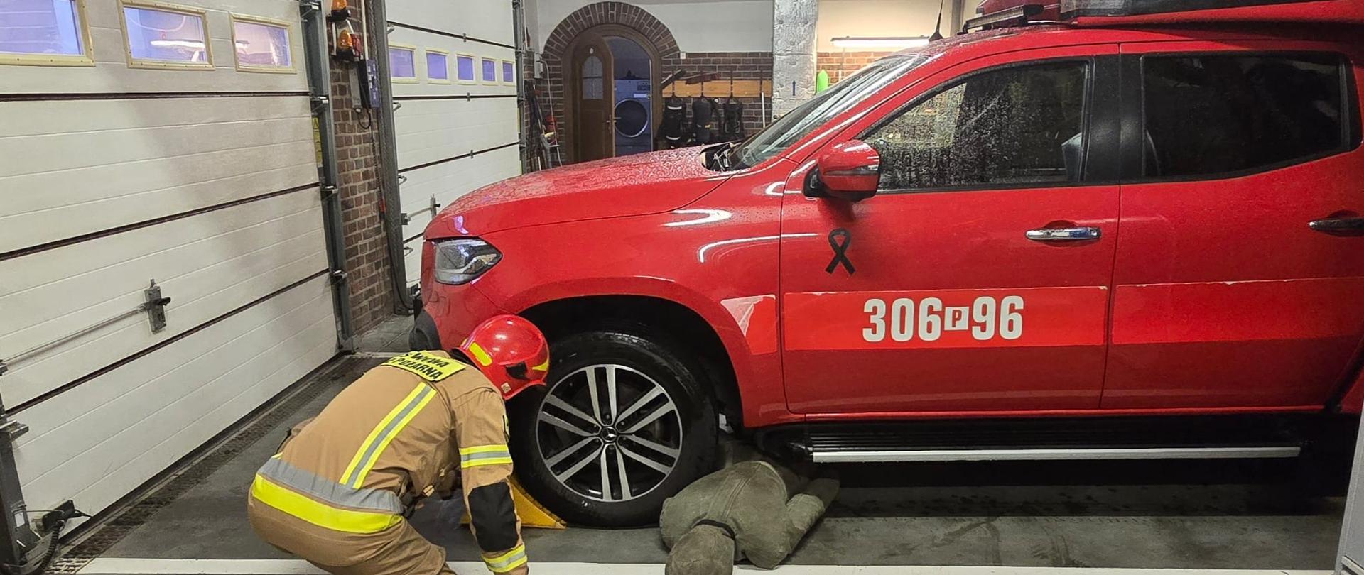 Strażak stabilizujący pojazd przy użyciu klinów samochodowych