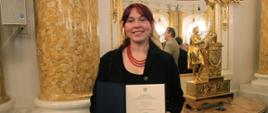 Na zdjęciu widzimy uczennicę Zuzannę Rumian trzymająca w rękach dyplom - Stypendium Ministra Kultury i Dziedzictwa Narodowego 2025. Fotografia została wykonana w Sali Balowej w Zamku Królewskim w Warszawie. Fot.: Marcin Klag