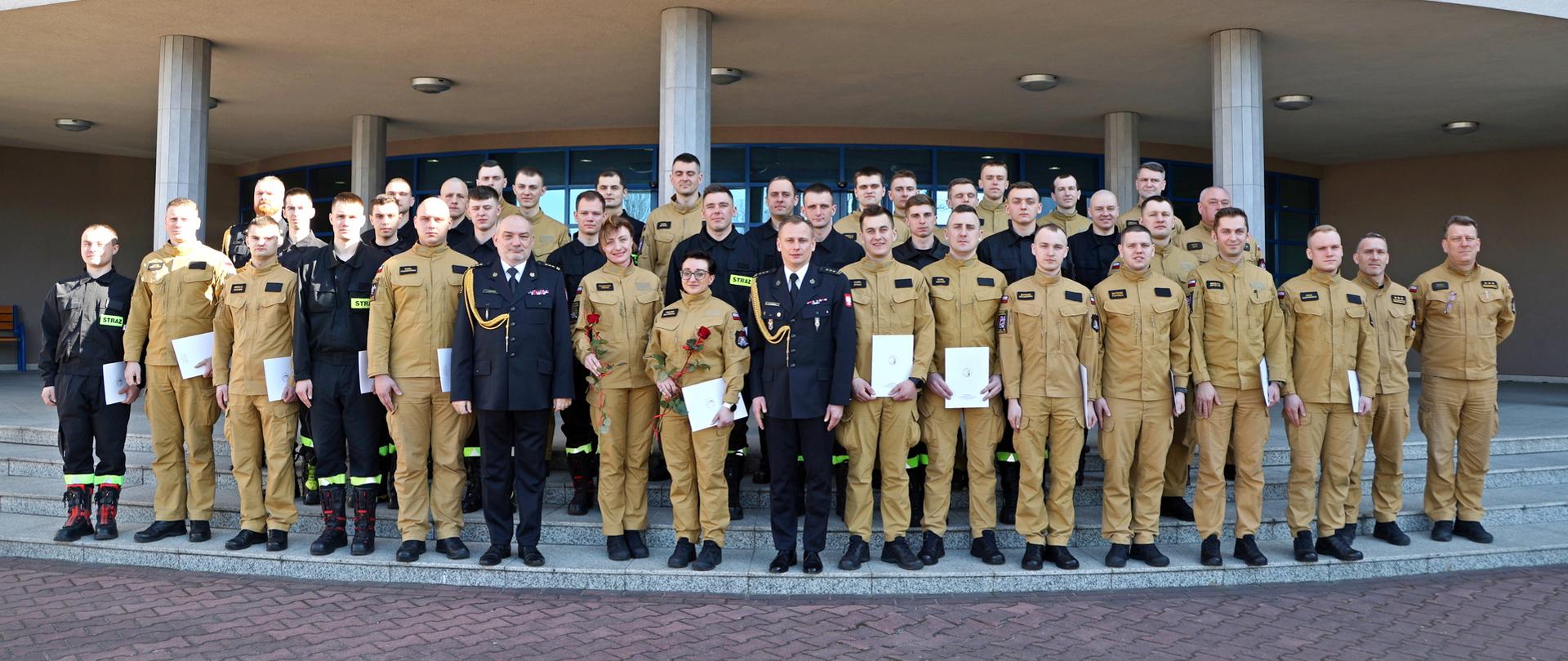 Pamiątkowe zdjęcie grupowe funkcjonariuszy PSP będących uczestnikami szkolenia podstawowego w zawodzie strażak (35 osób) w towarzystwie Komendanta Centralnej Szkoły PSP, Zastępcy Komendanta Centralnej Szkoły PSP oraz pięciu funkcjonariuszy CS PSP