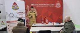 Na sali wykładowej strażacy prowadzą prelekcję na temat czujek dla mieszkańców powiatu trzebnickiego