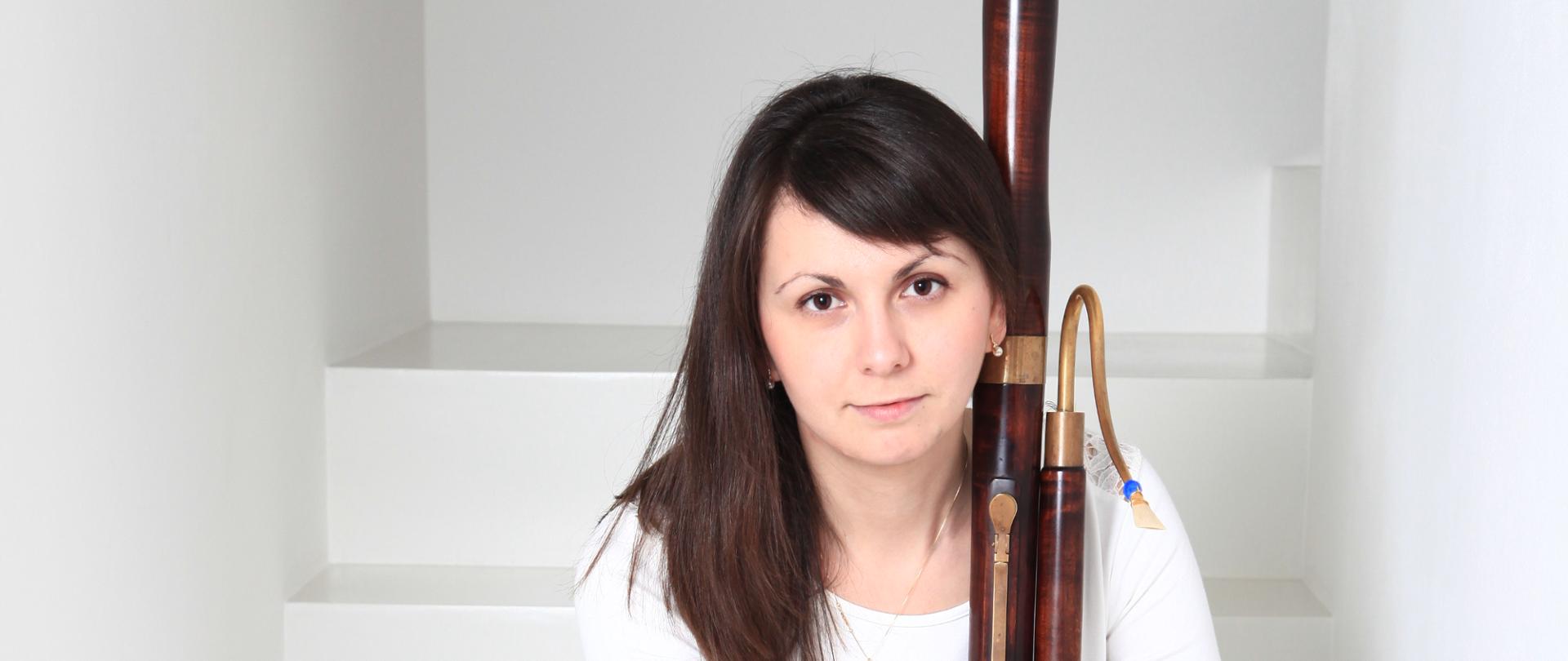 Kobieta siedzi na schodach i trzyma fagot.