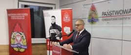Przemówienie Burmistrza Miasta Środa Wlkp. Andrzeja Mielocha podczas odprawy. W tle banery PSP Komendy Powiatowej PSP w Środzie Wielkopolskiej.
