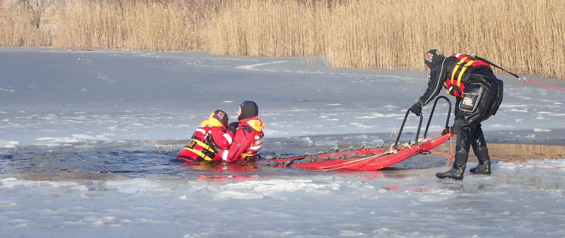 Deska lodowa dwóch ratowników ratuje poszkodowanego z przerębla