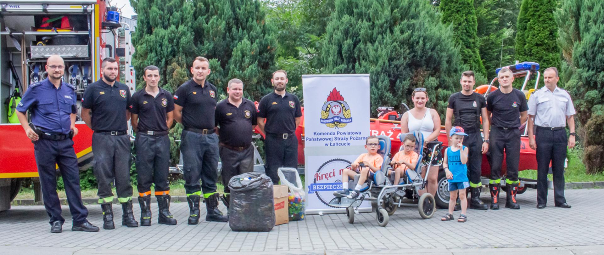 Zdjęcie przedstawia łódź ratowniczą Komendy Powiatowej Państwowej Straży Pożarnej w Łańcucie przed nią baner Komendy wraz z logiem akcji "kręci mnie bezpieczeństwo" obok od lewej stoją: policjant, strażacy Ochotniczej Straży Pożarnej w Handzlówce, kobieta z trójką chłopców, w tym dwóch na specjalnym wózku oraz strażacy Komendy Powiatowe Państwowej Straży Pożarnej w Łańcucie.