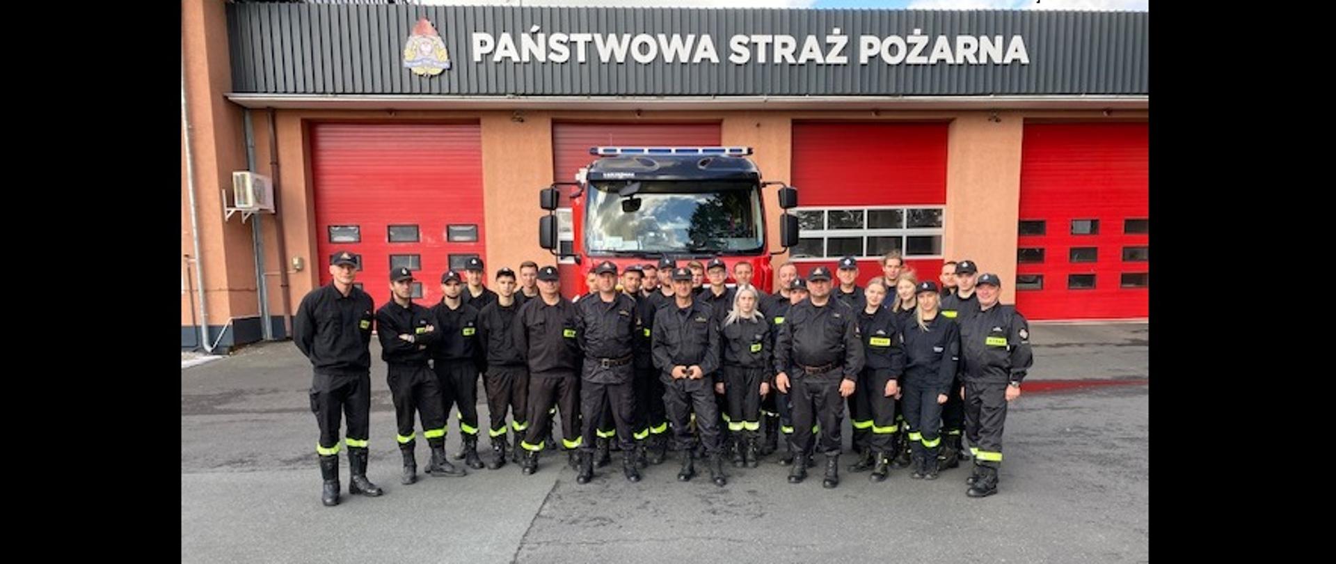 Zdjęcie grupowe strażaków PSP i strażaków ratowników OSP na tle JRG Polkowice oraz auta pożarniczego