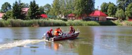 ratownicy poruszający się łodzią ratunkową po zbiorniku wodnym 