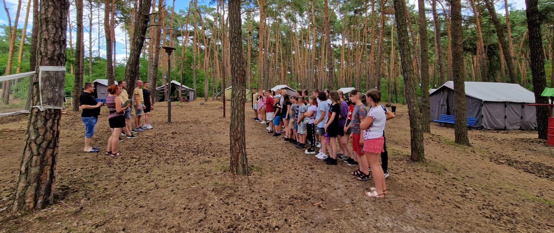Uczestnicy obozu podczas apelu w lesie na polanie.