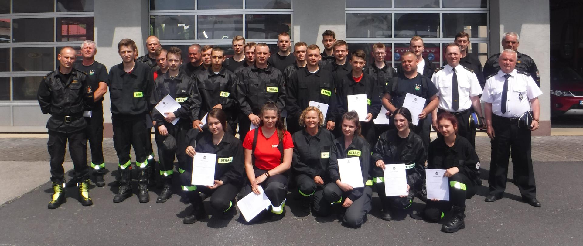 Na zdjęciu widzimy druhów OSP oraz funkcjonariuszy PSP pozujących do grupowego zdjęcia na tle budynku Jednostki Ratowniczo Gaśniczej w Leżajsku.