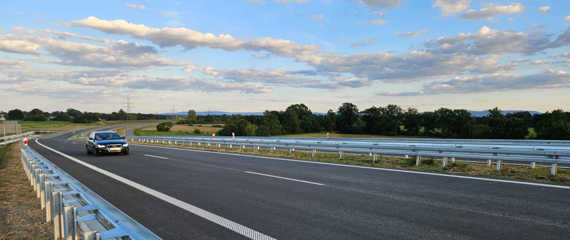 Obwodnica Oświęcimia, nowy odcinek, dwie jezdnie z dwoma pasami ruchu, w oddali pola, zadrzewienia, wzgórza