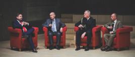 Zaproszeni goście siedzą w fotelach i prowadzą dyskusje. 