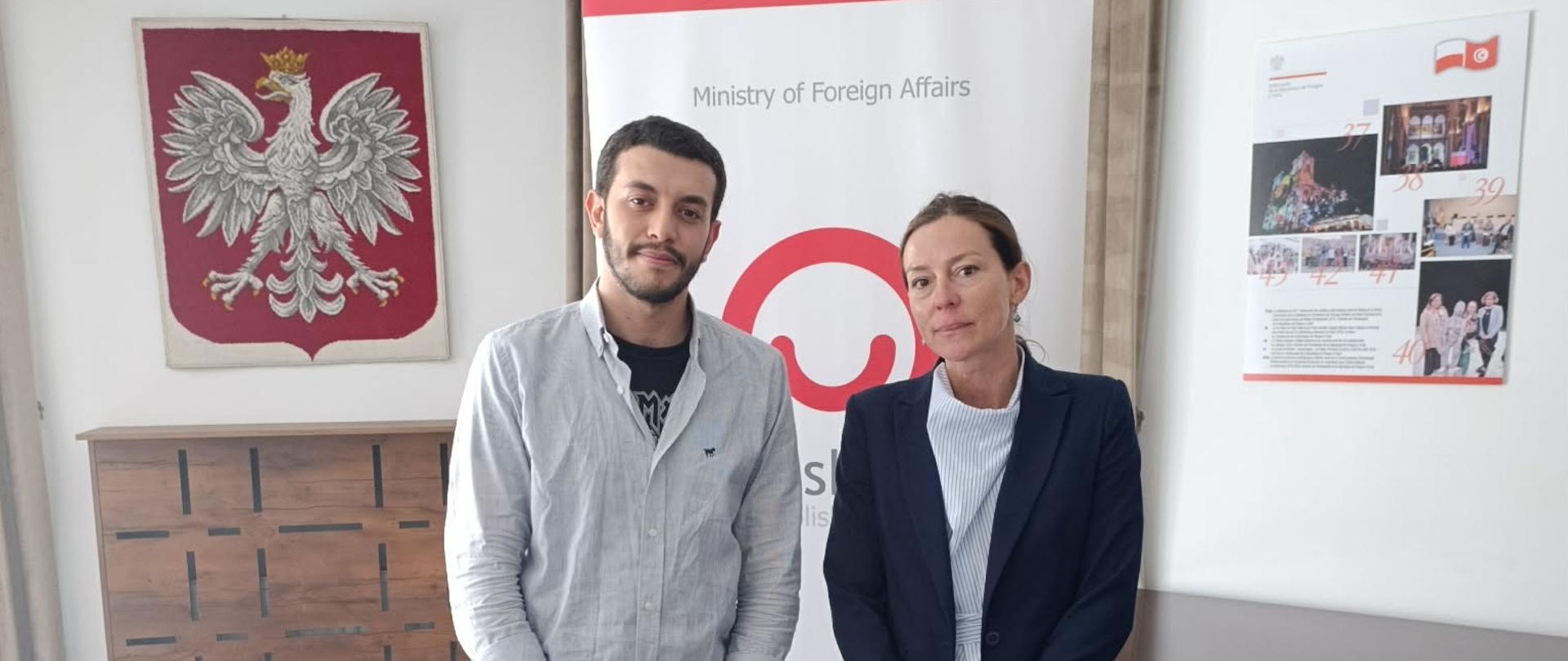 kobieta i mężczyzna stoją na tle logo Polish Aid