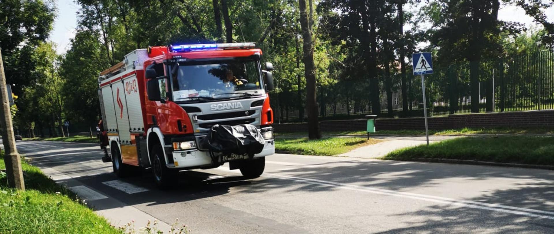 Pojazd gaśniczy z włączonymi sygnałami świetlno-dźwiękowymi podczas jazdy do zdarzenia.