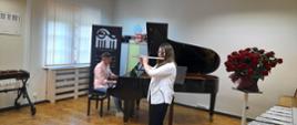 Zdjęcie przedstawia uczennicę grającą na flecie podczas koncertu absolwentów.