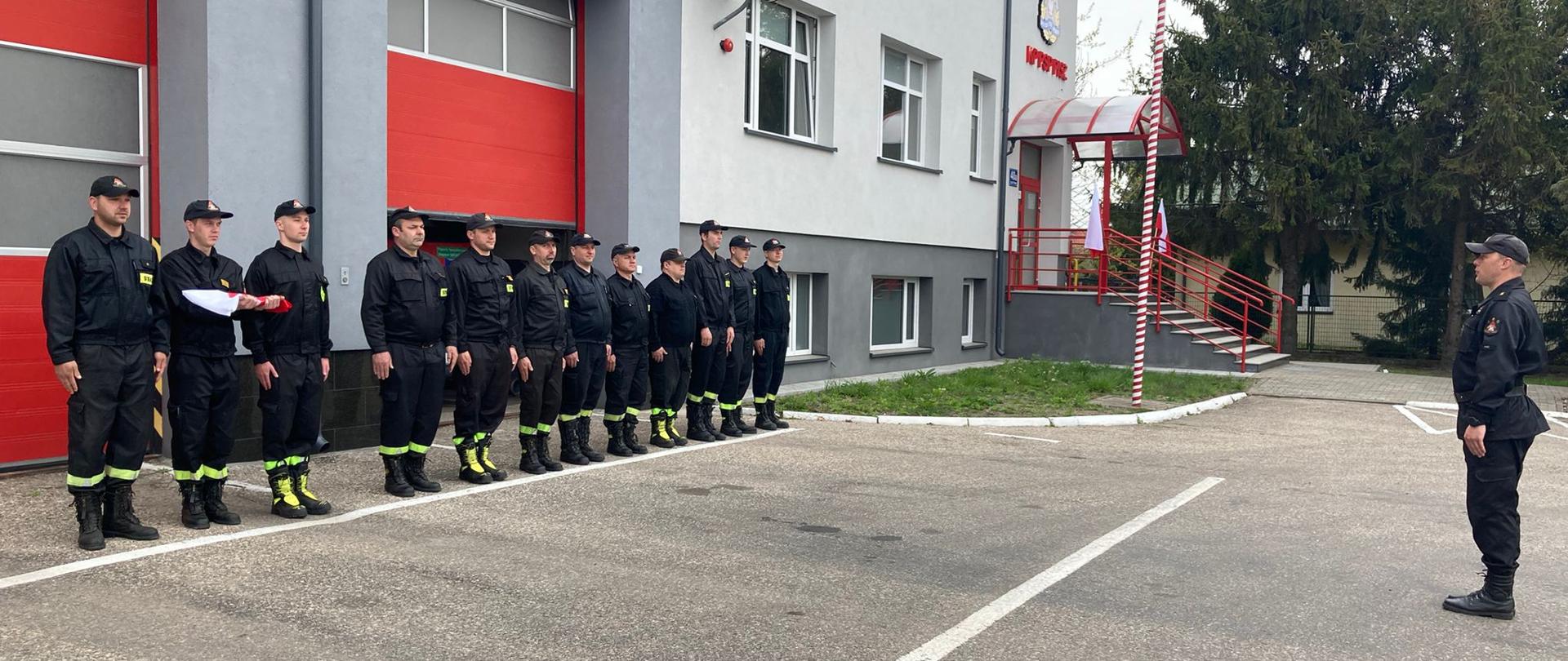 Strażacy stojący przed budynkiem Komendy