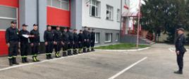 Strażacy stojący przed budynkiem Komendy
