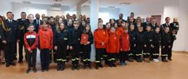 Przedstawiciele Młodzieżowych Drużyn Pożarniczych strażacy Państwowej Straży Pożarnej oraz ochotniczych straży pożarnej stoją obok siebie w rzędach.