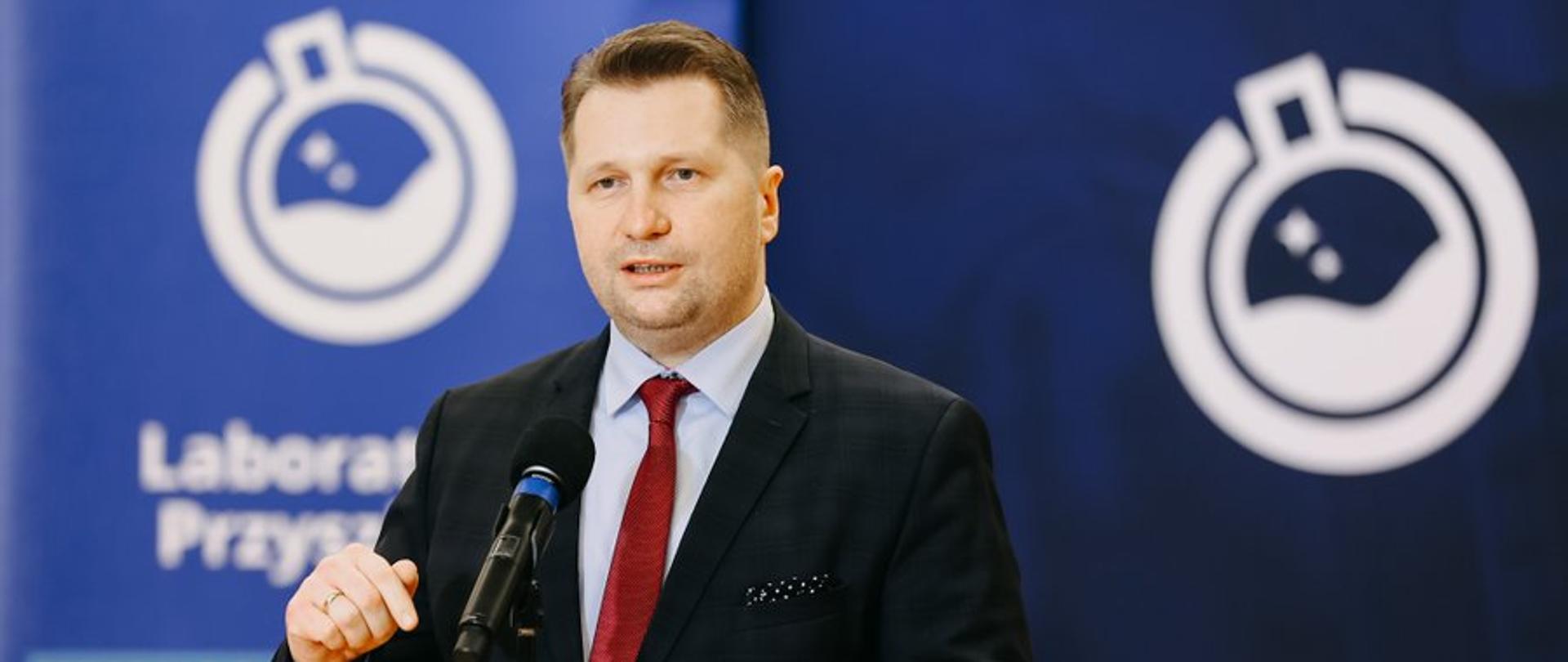 Minister Przemysław Czarnek przemawia podczas konferencji w Nowej Sarzynie. Stoi przed mikrofonem, za nim stoi baner z napisem Laboratoria Przyszłości.