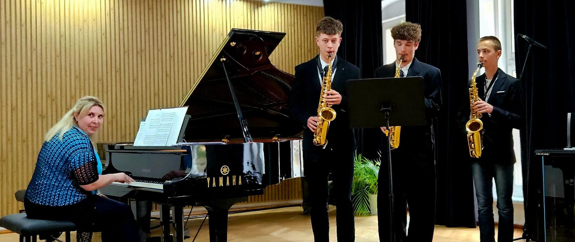 Galeria 18 zdjęć z koncertu uczniów klas saksofonu i klarnetu, który odbył się 14 maja 2025 w auli PSM w Kłodzku. Młodzi wykonawcy grają na klarnecie i saksofonie na scenie sali koncertowej.