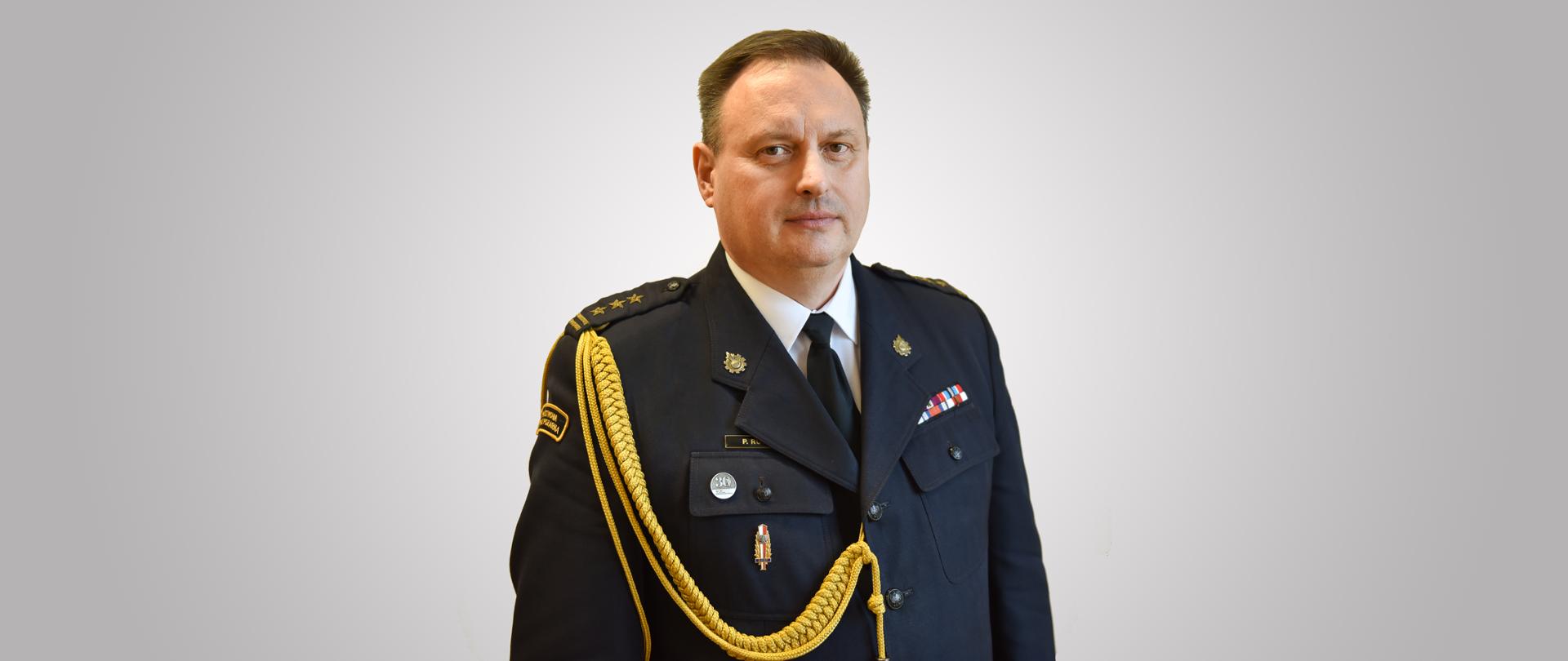 zdjęcie przedstawia starszego brygadiera Piotra Rudeckiego Łódzkiego Komendanta Wojewódzki PSP w mundurze wyjściowym. Zdjęcie portretowe