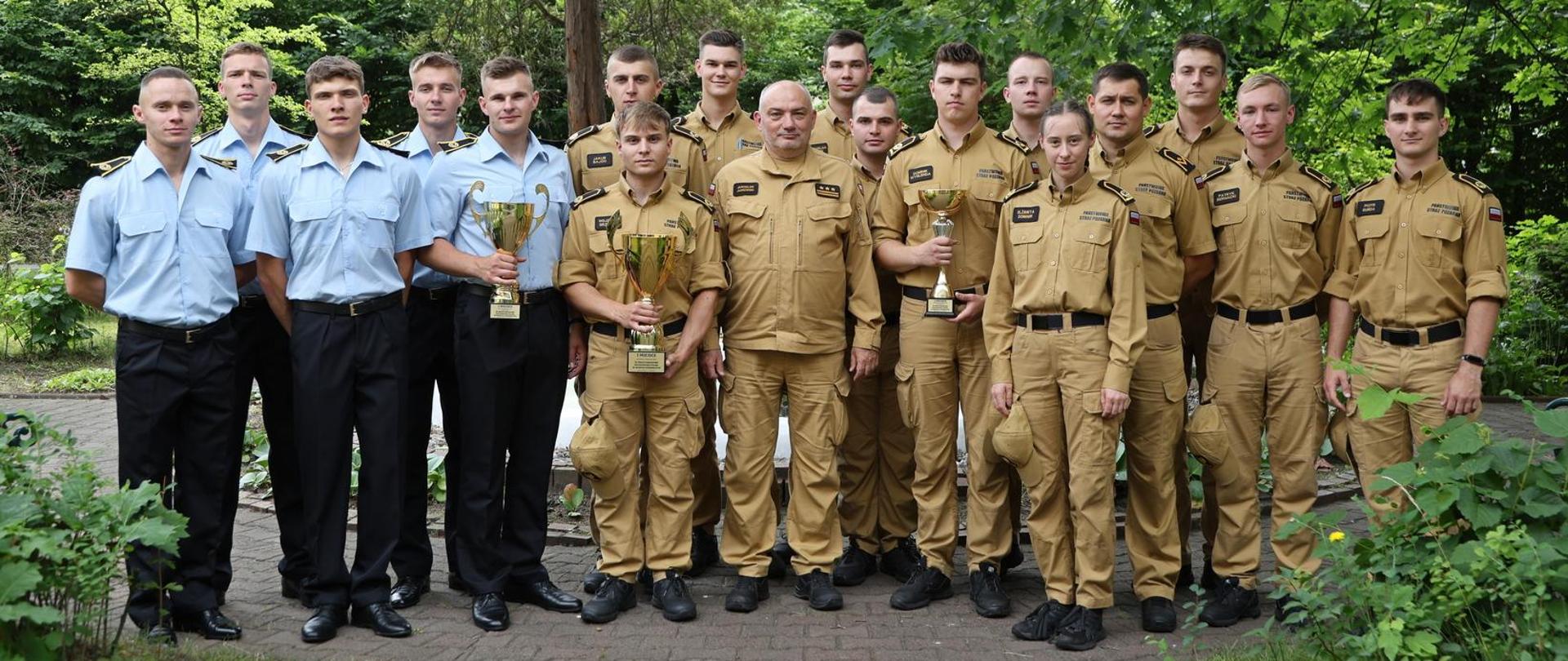 Pamiątkowe zdjęcie grupowe kadetów stanowiących drużynę reprezentującą Szkołę podczas XL Międzynarodowych Mistrzostw Polski w Sporcie Pożarniczym wraz z trenerem w towarzystwie Komendanta Centralnej Szkoły PSP