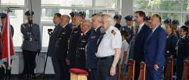 Przedstawiciele służb mundurowych oraz zaproszeni goście stoją na baczność.