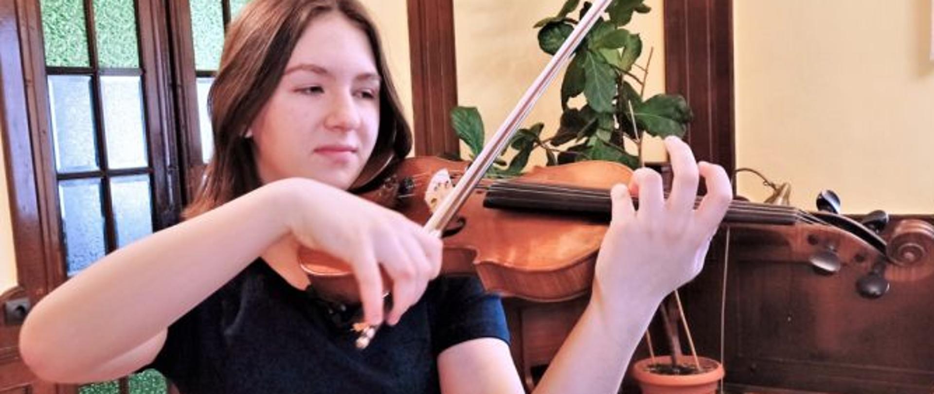Zdjęcie kolorowe przedstawiające uczennicę ze skrzypcami.