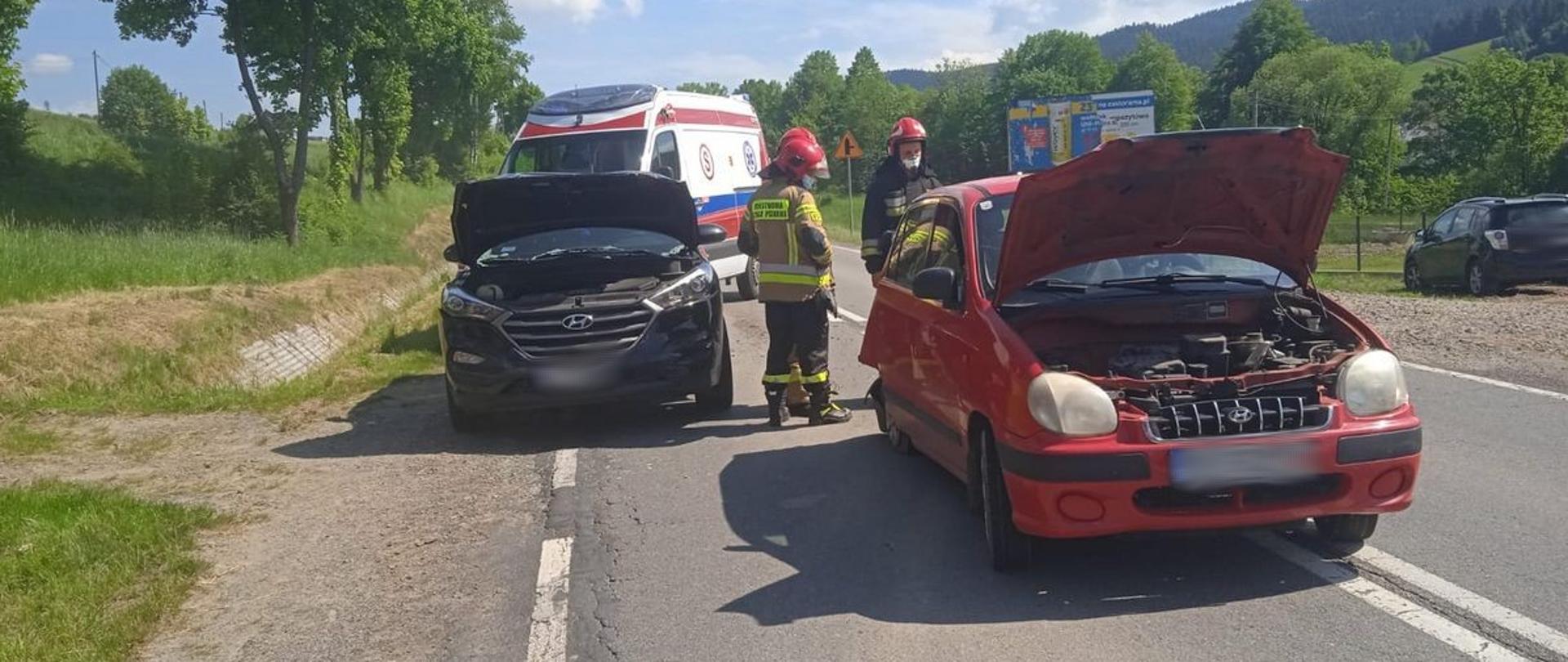 Samochody uczestniczące w zdarzeniu pomiędzy nimi strażacy a za nimi karetka Pogotowia ratunkowego.