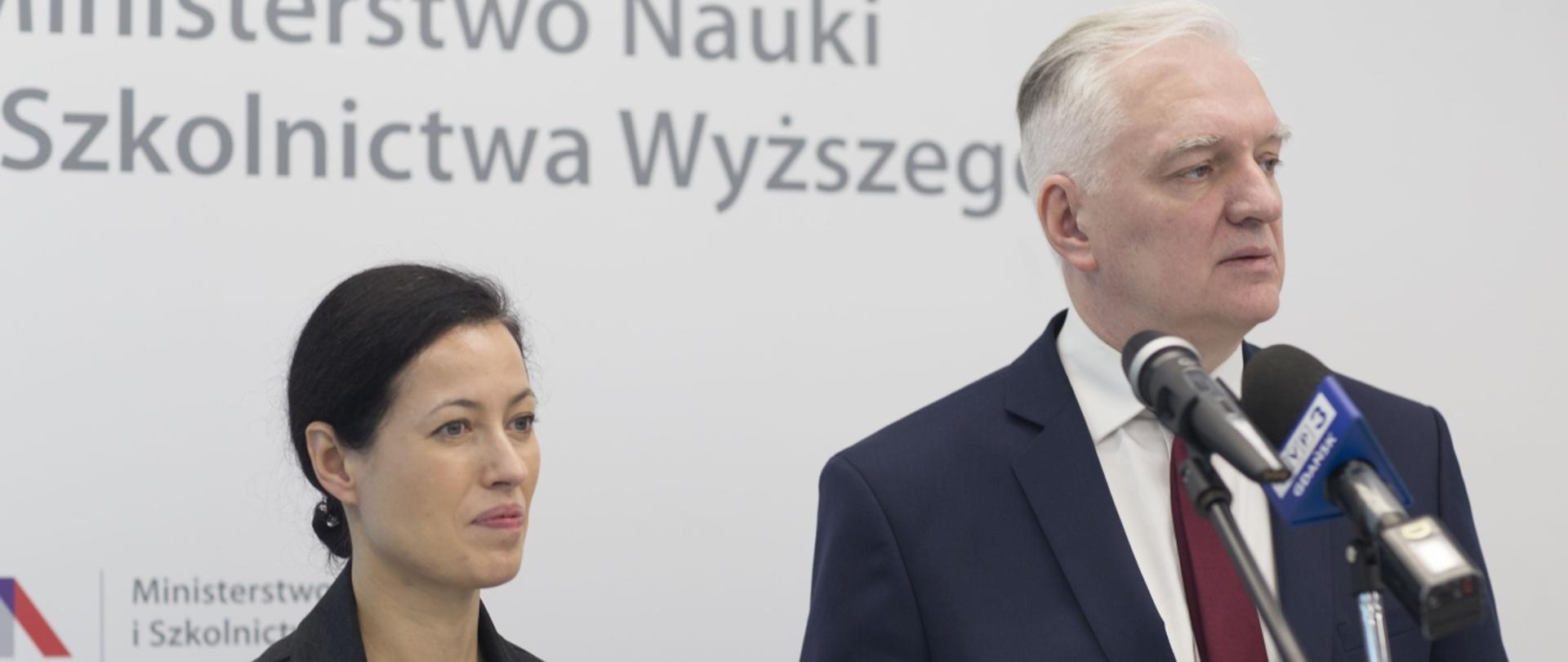 Ministrowie Jarosław Gowin i Anna Budzanowska stoją na tle białej ściany