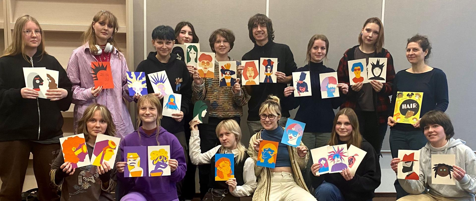 Zdjęcie - w centrum grupa uczniów prezentująca swoje prace graficzne.