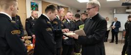 Na zdjęciu w trakcie uroczystego spotkania wigilijnego Kapelan Strażaków częstuje załogę KP PSP w Rypinie opłatkiem 