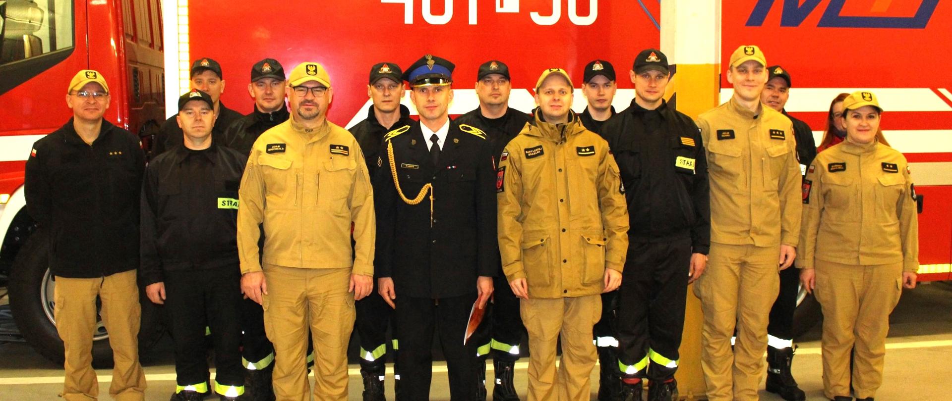 Zdjęcie przedstawia strażaków w trakcie uroczystego wręczania decyzji jubileuszowej.
W tle pomieszczenie garaży JRG.
