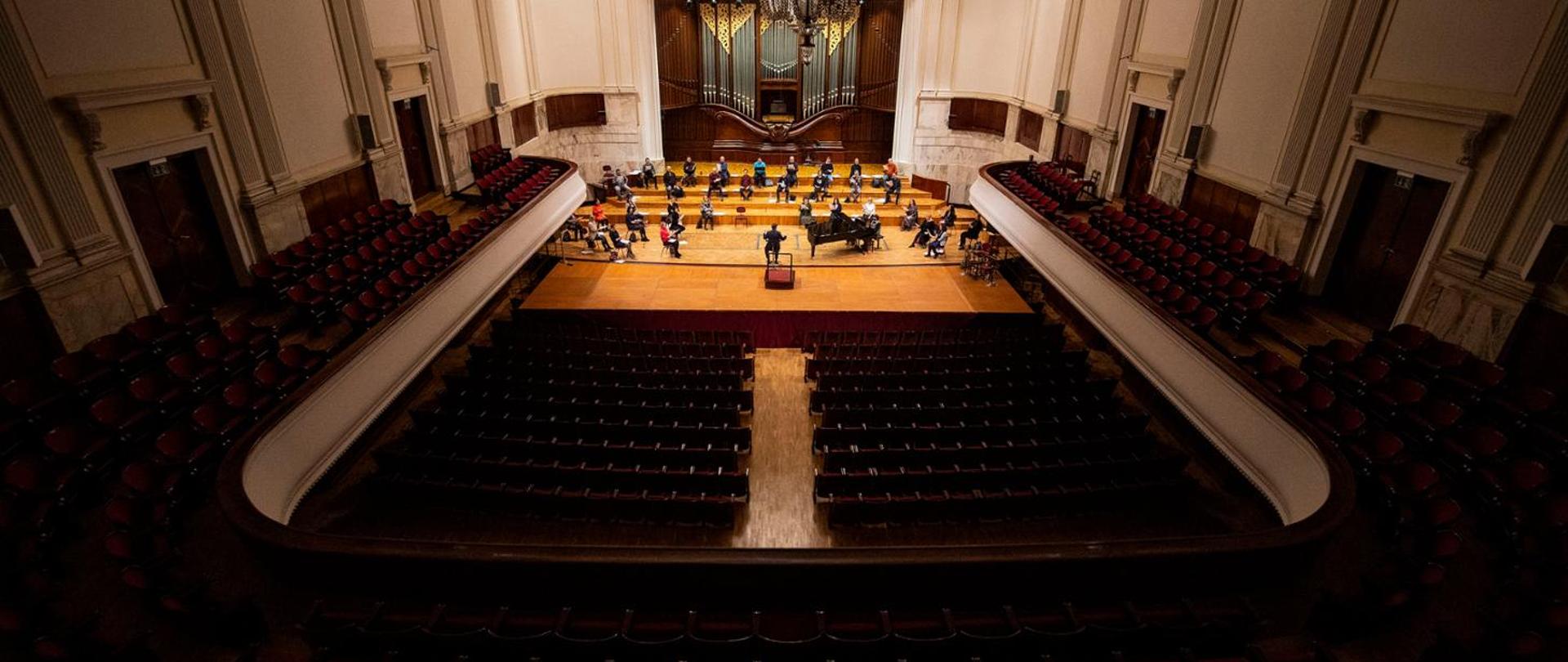 scena filharmonii, na niej rozstawieni muzycy z instrumentami, miejsca dla publiczności są puste.