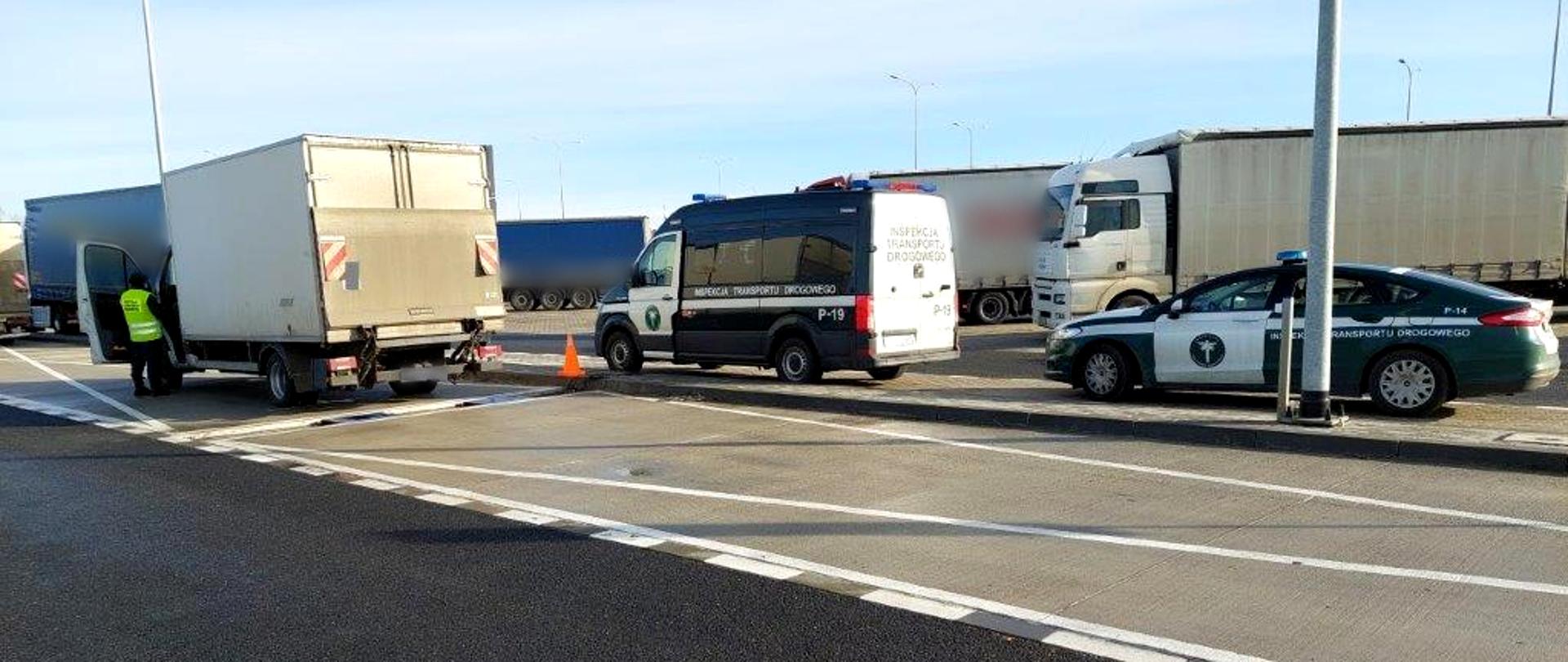 Kontrola dolnośląskiej ITD w punkcie wagowym przy S3. Po lewej jeden z zatrzymanych dostawczaków, przy nim stoi inspektor ITD. Po prawej dwa samochody Inspekcji Transportu Drogowego. W tle zaparkowane przy drodze ekspresowej nr 3 samochody ciężarowe.